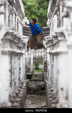 Un jeune homme monter les stupas de blanc la pagode Sandamuni à Mandalay, Myanmar (Birmanie). Banque D'Images