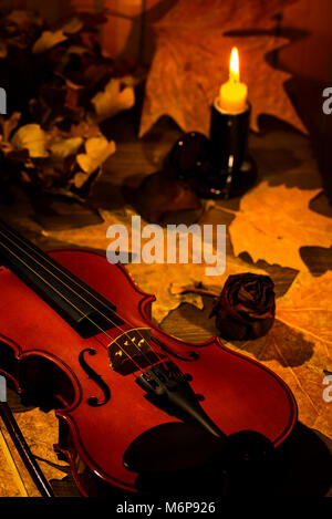 Violon, bougie allumée et feuilles d'automne sur la table Banque D'Images