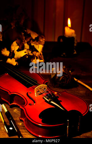 Violon, bougie allumée et feuilles d'automne sur la table Banque D'Images