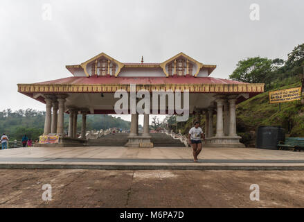 Talakaveri, Inde - le 31 octobre 2013 : rouge et or Mandapam comme porte d'entrée au domaine du sanctuaire de printemps de la rivière Kaveri. Ciel d'argent. Les gens clim Banque D'Images