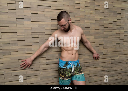 Portrait d'un jeune homme en bonne forme physique montrant son corps bien formé - Remise en forme musculaire Bodybuilder Athletic Model Posing Après Exercices sur mur près de Banque D'Images