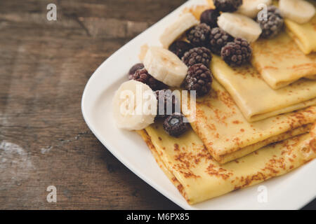 Pancakes à la banane et des baies congelées sur fond sombre. Des crêpes aux bananes et fruits Banque D'Images