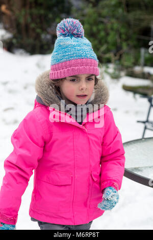 Cute little girl jouer à l'extérieur dans la neige en hiver. Portrait vertical demi-longueur Banque D'Images