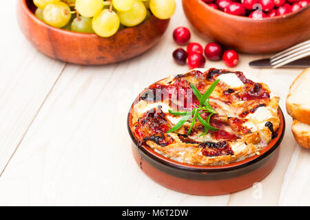 Camembert au four avec sauce aux canneberges et au romarin servi avec du pain grillé et des raisins Banque D'Images