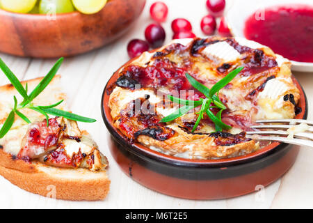 Camembert au four avec sauce aux canneberges et au romarin servi avec du pain grillé et des raisins Banque D'Images