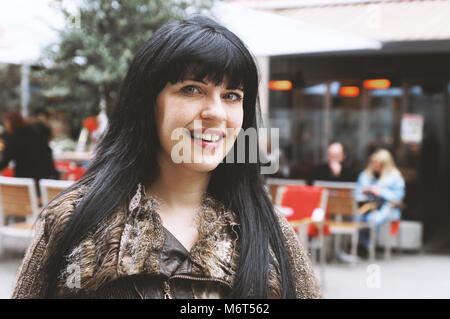 Jeune femme dans la rue piétonne du centre-ville en face d'un café en plein air Banque D'Images