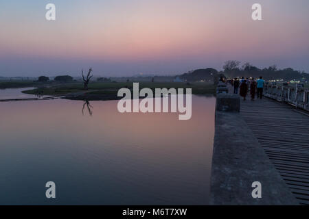 Lac et certaines personnes au pont U Bein à Amarapura près de Mandalay en Birmanie au coucher du soleil. C'est le plus ancien et le plus long pont en teck du monde. Banque D'Images