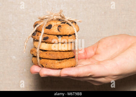 Mains tiennent les cookies au chocolat cookies aux pépites de chocolat attachés avec un ruban. Banque D'Images