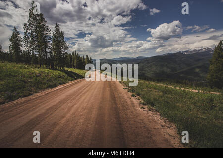 Vue à couper le souffle d'un chemin de terre sinueux au sommet de la montagne Vail, avec une vue magnifique des Montagnes Rocheuses en toile de fond, Vail, Colorado Banque D'Images