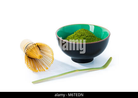 Green thé matcha en poudre dans un bol et mélanger avec une cuillère en bambou isolé sur fond blanc, de face, close-up. Banque D'Images