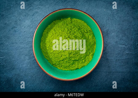 La poudre de thé vert matcha dans un bol sur fond ardoise, vue de dessus, close-up Banque D'Images