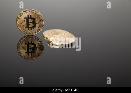 Devise Crypto. Les bitcoins or sur verre gris avec reflet Banque D'Images