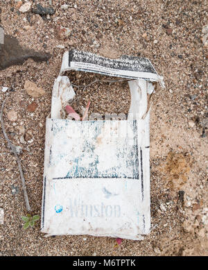 Les pousses de plante poussant par paquet de cigarettes jetées près de Spanish beach Banque D'Images