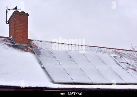 Panneaux d'énergie solaire sur un toit couvert de neige au royaume-uni Banque D'Images