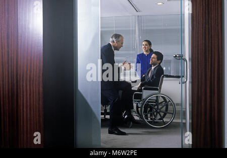 Historique 1995 CAUCASIAN BUSINESS MAN AUX PERSONNES HANDICAPÉES PERSONNES HANDICAPÉES L'HOMME D'AFFAIRES ASSIS DANS FAUTEUIL ROULANT DANS OFFICE Banque D'Images