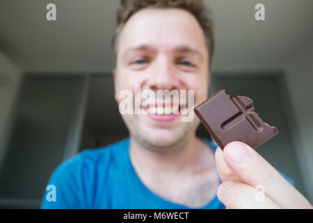 Young caucasian guy manger un seul chocolat Banque D'Images