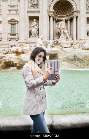 Jolie jeune femme woman smiling touristiques faisant self portrait avec tablette avec en arrière-plan de la fontaine de Trevi, Rome Italie monument monument Banque D'Images