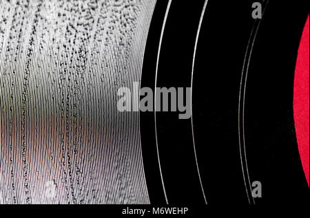 Extreme close up of vinyl record surface noire, creux de la texture et de l'espace de copie l'étiquette sur le côté rouge Banque D'Images