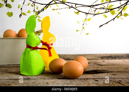 Décoration de Pâques avec des lapins et des œufs sur table en bois et des brunchs d'arbre. Banque D'Images