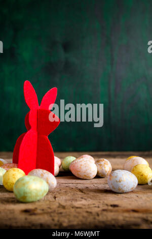 Lapin de Pâques sur table en bois avec des œufs colorés. Fond sombre. Copier l'espace. Banque D'Images