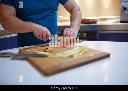 Mains de man chopping piment et le gingembre sur une planche en bois Banque D'Images