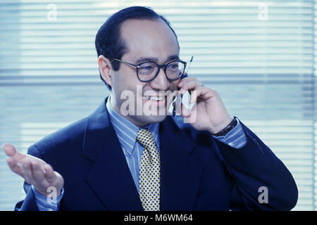 1998 PORTRAIT HISTORIQUE DE ASIAN BUSINESS MAN TALKING ON MOBILE TÉLÉPHONE CELLULAIRE IN OFFICE Banque D'Images