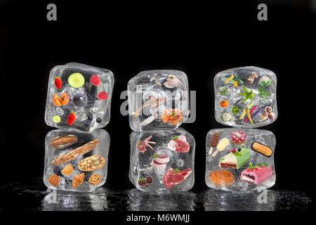 Concept de produits congelés : fruits, légumes, poissons, viandes, épices, herbes, pâtisserie ont été gelés à l'intérieur des cubes de glace sur fond noir Banque D'Images