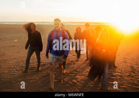 Un groupe d'amis marche sur la plage au coucher du soleil Banque D'Images