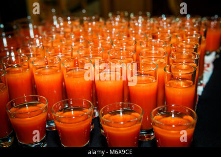 Ensemble de verres avec du jus d'orange disposés en rangées sur le noir sur la table de banquet service traiteur Banque D'Images