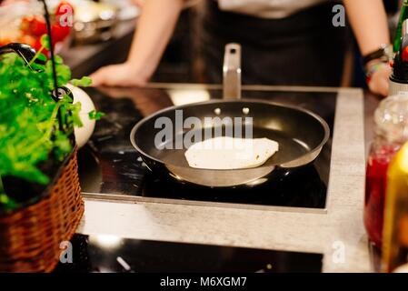 La friture femme tortillas sur le poêle dans la cuisine Banque D'Images