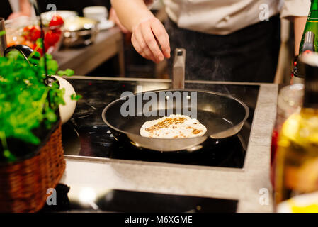 La friture femme tortillas sur le poêle dans la cuisine Banque D'Images