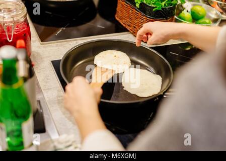 La friture femme tortillas sur le poêle dans la cuisine Banque D'Images