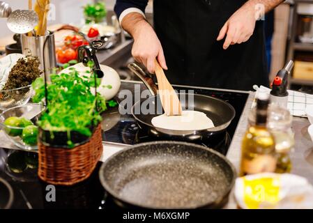 La friture femme tortillas sur le poêle dans la cuisine Banque D'Images