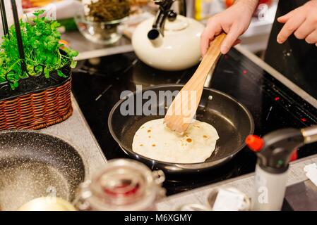 La friture femme tortillas sur le poêle dans la cuisine Banque D'Images