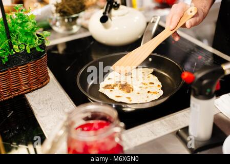 La friture femme tortillas sur le poêle dans la cuisine Banque D'Images