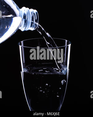 L'eau s'écoule à partir d'une bouteille dans un verre Banque D'Images