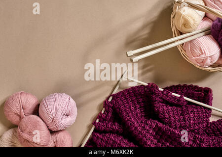 Boules de fil de laine mérinos, tricot sur aiguilles à tricoter sur une surface de couleur beige. Vue d'en haut Banque D'Images