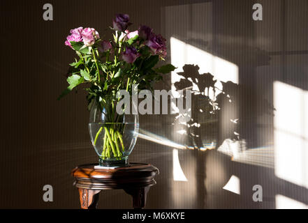 Un vase de roses près d'une fenêtre avec ombres, Hanbury, Tutbury, Burton upon Trent, Staffordshire. UK Banque D'Images