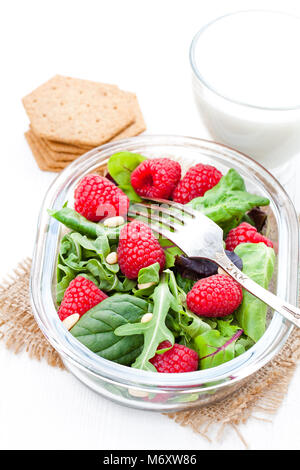 Salade verte avec la roquette et les baies et les noix de pin sur le tableau blanc avec du yogourt Banque D'Images