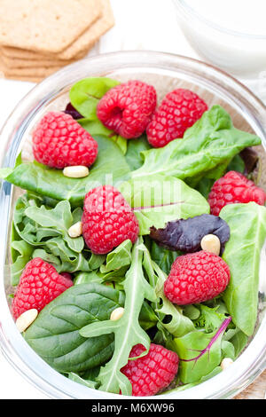 Salade verte avec la roquette et les baies et les noix de pin sur blanc Banque D'Images