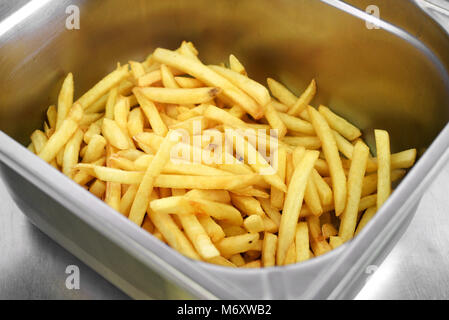 Le métal casier rempli de golden croustillant de croustilles de pommes de terre ou de frites prêt à être servi en accompagnement dans un restaurant Banque D'Images