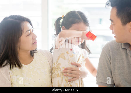 Les parents réconfortant de pleurer sa fille. La famille asiatique à la maison, mode de vie naturel à l'intérieur. Banque D'Images