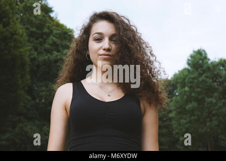 Adolescente brune avec de long cheveux bouclés dans la nature Banque D'Images