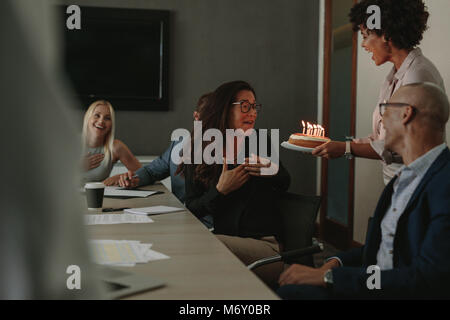 Les employés de bureau celebrating birthday of female colleague avec gâteau dans la salle de conférence. Collègue féliciter vos collègues sur un anniversaire Banque D'Images