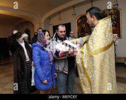 Baptême pour bébé en église rurale. Souverain sacrificateur, debout en face de la femme et l'homme avec un bébé sur les mains et la lecture de la Bible. Janvier 7,2018. Bucha, Ukraine Banque D'Images