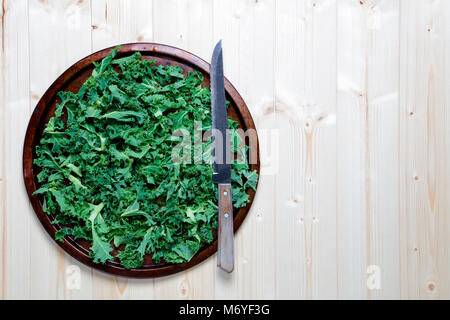 Kale haché préparé sur l'ancien plateau en métal à l'aide d'un couteau Banque D'Images