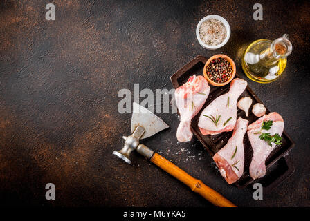 Les viandes, prêt pour grill ou barbecue cuisses de poulet, avec des herbes et épices, l'arrière-plan foncé n rusty copy space Banque D'Images