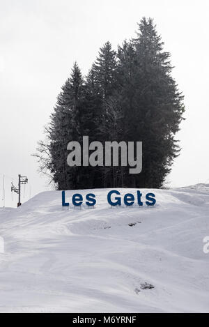 Un grand panneau en bleu pour la station de ski Les Gets sur une piste de ski à la station avec quatre pins à l'arrière-plan Haute Savoie France Banque D'Images