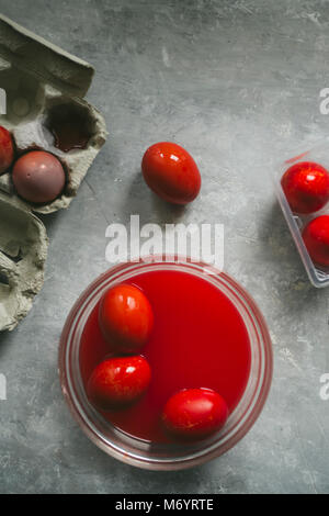 Les œufs de couleur rouge avec teinte rouge s'affichent sur une grille métallique haut vue sur un fond de béton gris Banque D'Images