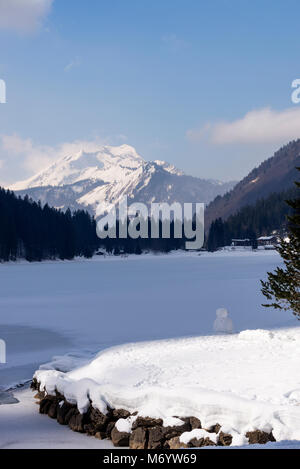 Le magnifique Lac de Montriond avec gelé recouvert de neige Roc d'Enfer ardent de la montagne Haute Savoie Portes du Soleil France Banque D'Images